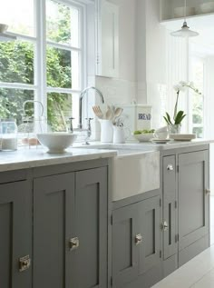 a kitchen filled with lots of white counter tops and gray cabinets next to a window