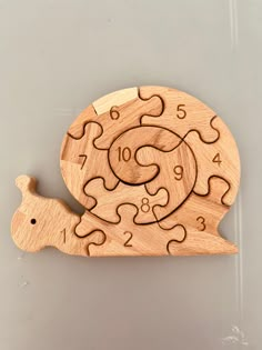 a wooden clock that is shaped like a snail and has numbers on the front side