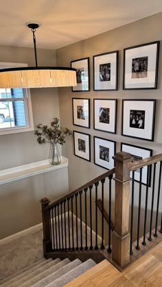 a staircase with pictures hanging on the wall above it and a vase filled with flowers