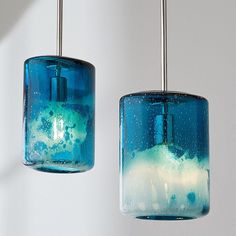 two blue and green glass lights hanging from a ceiling