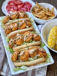 two trays filled with hot dogs, corn on the cob and french fries