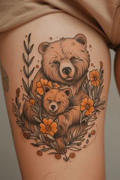 a woman's thigh with a bear and cub tattoo on it, surrounded by flowers