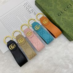 four gucci key chains sitting next to an open book