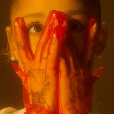 a woman holding her hands up to her face and covering her eyes with red net