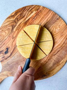 a person is cutting cheese on a wooden board