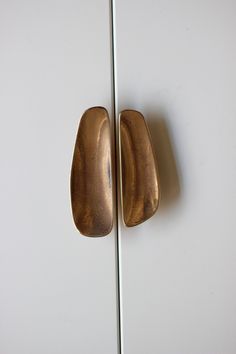 two brass handles on a white cabinet