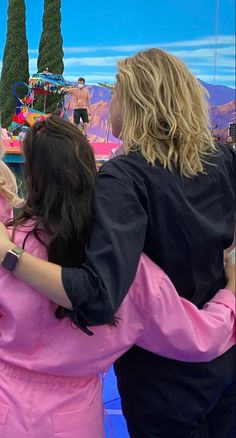 two women hugging each other while standing in front of a blue screen with people on it