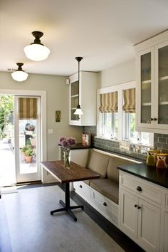 a kitchen with white cabinets and black counter tops next to a wooden dining room table