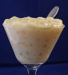 a dessert in a glass with a spoon sticking out of it's top, on a blue background