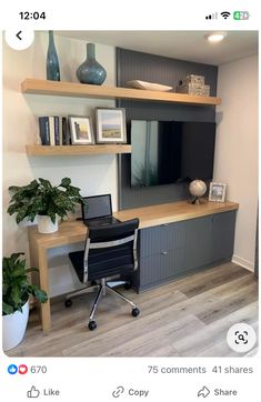 a computer desk sitting in front of a tv on top of a wooden shelf next to a potted plant