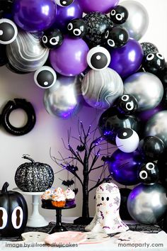 a table topped with lots of purple and black balloons