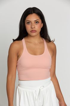 Our Peach Racerback Crop Tank features a slight cropped fit and racerback style that is the perfect go-to athletic top. It is complete with sweat-wicking material and a double layer, built-in-removable padded bra. 75% Nylon, 25% Spandex Built in / Removable Padding Model Details: Modeled in size: Small Model Waist: 30 Model Bust: 34 Model Height: 5'6 Spring Crop Top With Built-in Bra For Gym, Light Exercise Racerback Sports Bra With 4-way Stretch, Functional Racerback Crop Top With Medium Support, Functional Medium Support Racerback Crop Top, Athleisure Racerback Crop Top, Functional Racerback Crop Top For Training, Athleisure Tank Sports Bra, Casual Sports Crop Top With Built-in Bra, Casual Cropped Top For Light Exercise