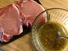 two pieces of raw meat sitting on top of a cutting board next to a bowl of olive oil