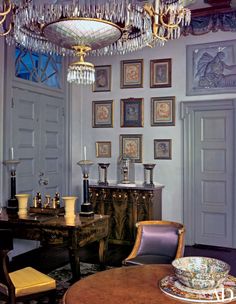 an old fashioned dining room with chandelier and pictures on the wall