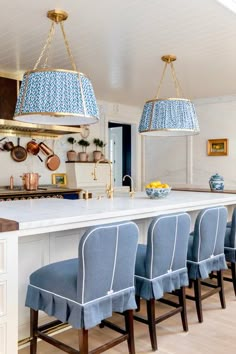 a kitchen island with blue chairs and hanging lights