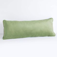 a green pillow sitting on top of a white bed