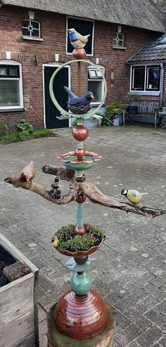 a bird feeder with birds sitting on it's sides in front of a house