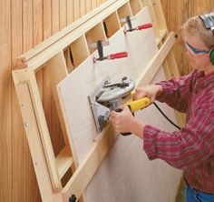 a woman in headphones is working on a piece of wood with a drill and screwdriver