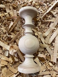 a white wooden object sitting on top of wood shavings in a pile of wood chips