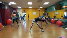 a group of people in a gym doing exercises with exercise balls on their feet and arms