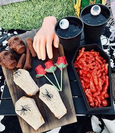 halloween treats are laid out on a picnic table with fake hands and spider webs