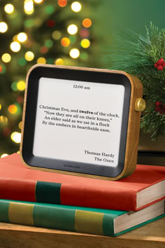 a christmas tree is in the background with a book on it and an open tablet