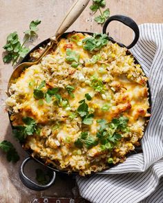 a casserole dish with rice and vegetables in it on a table next to a spoon