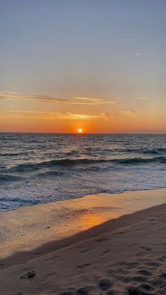 the sun is setting over the ocean with waves