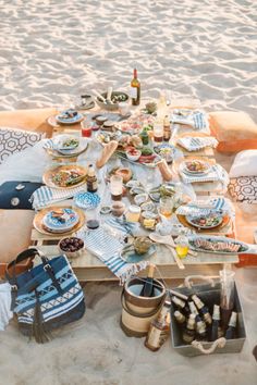 a table set up on the beach with food and drinks