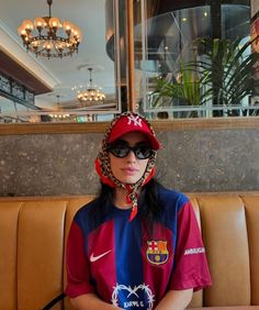 a woman sitting on top of a brown couch wearing a red and blue soccer jersey