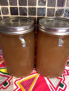 two jars filled with brown liquid sitting on top of a table