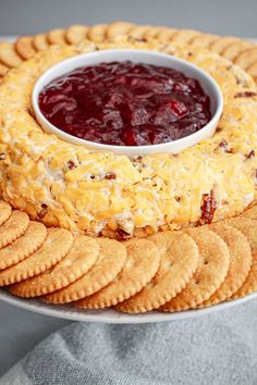 a platter with crackers, cheese and cranberry sauce on it is shown