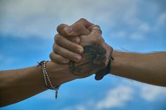 two people holding hands with sky in the background