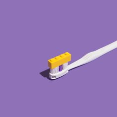 a yellow and white toothbrush on a purple background