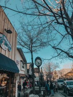 people are walking down the sidewalk in front of shops and stores on a sunny day