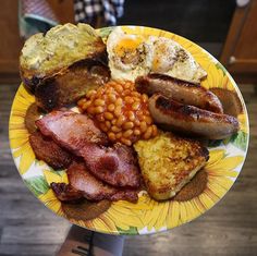 a yellow plate topped with bacon, beans and eggs