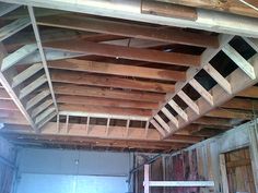 the inside of a building that is being built with wooden beams and ladders hanging from the ceiling