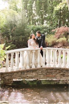 a bride and groom kissing on a bridge