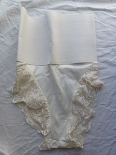 Vintage Frederick's of Hollywood panty, girdle, tummy hugger shapewear. Made of 85% nylon and 15% spandex, in an off-white cream color. The top is made of a firm and wide elastic band. The band is 10.5 inches across un-stretched (21 inches circumference) to 14 inches across (28 inches circumference) fully stretched. The gusset is unlined. The legs are lined with lace. The entire piece measured from the top to the crotch is 15.5 inches, with an extra 2-inch stretch. I'm guessing this will fit a modern size Medium. Please keep in mind, this is shapewear, so it is meant to be fitted and not loose. In good condition. I did not see any issues. Fitted White Underbust Shapewear, Elegant Fitted Shapewear With Boning, Elegant Fitted Shapewear With Lace Trim, Fitted Cream Bottoms With Lace Trim, Full Coverage Stretch Shapewear For Daywear, Fitted Shapewear Briefs With Wide Waistband, Daywear Bottoms With Built-in Bra And Stretch, Fitted High Waist Bottoms With Boning, Elegant Shaping Bottoms For Daywear