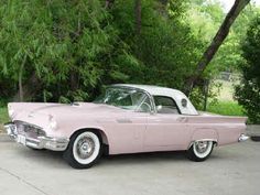 an old pink car parked in front of some trees