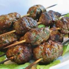 meatballs and skewers are sitting on a plate with lettuce leaves