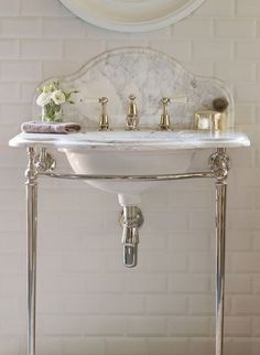 a white sink sitting under a mirror next to a wall mounted faucet in a bathroom