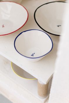 three bowls sitting on top of a white shelf