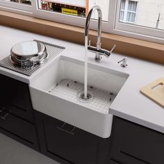 a white kitchen sink sitting under a window next to a cutting board and utensils