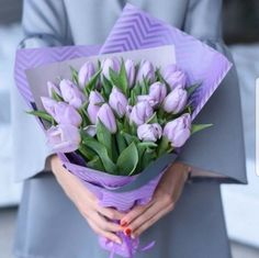 a woman holding a bouquet of purple tulips