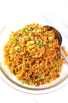 a bowl filled with noodles and vegetables on top of a white table cloth next to a spoon