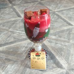 a glass filled with red liquid sitting on top of a wooden table