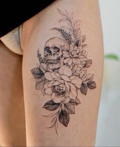 a woman's thigh with a skull and flowers on it