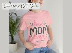 a woman wearing a pink t - shirt with the words best mom ever printed on it