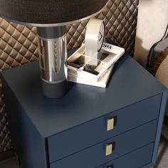 a nightstand with a lamp on top of it next to a blue chest of drawers